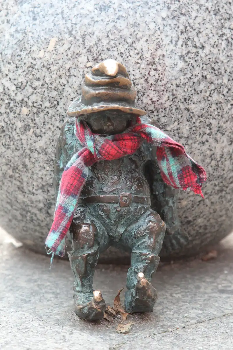 Un petit personnage en bronze de Wrocław, habillé d’une écharpe rouge.